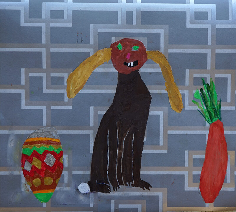 red and green easter egg, black bunny with yellow ears and an orange and green carrot on grey wallpaper